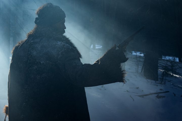 Taylor Kitsch holds up a gun in American Primeval.