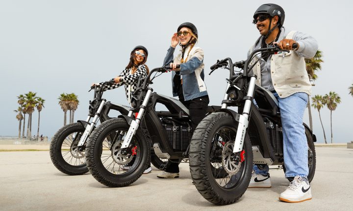 Three people on Segway Xyber e-Bikes near the beach with palm trees in the background.