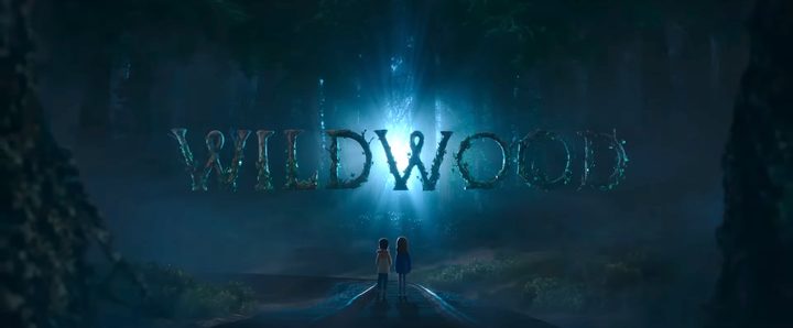 Two children standing in front of the title card for "Wildwood."