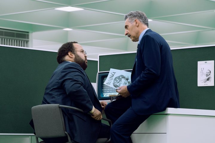 Zach Cherry sits with John Turturro in Severance season 2.