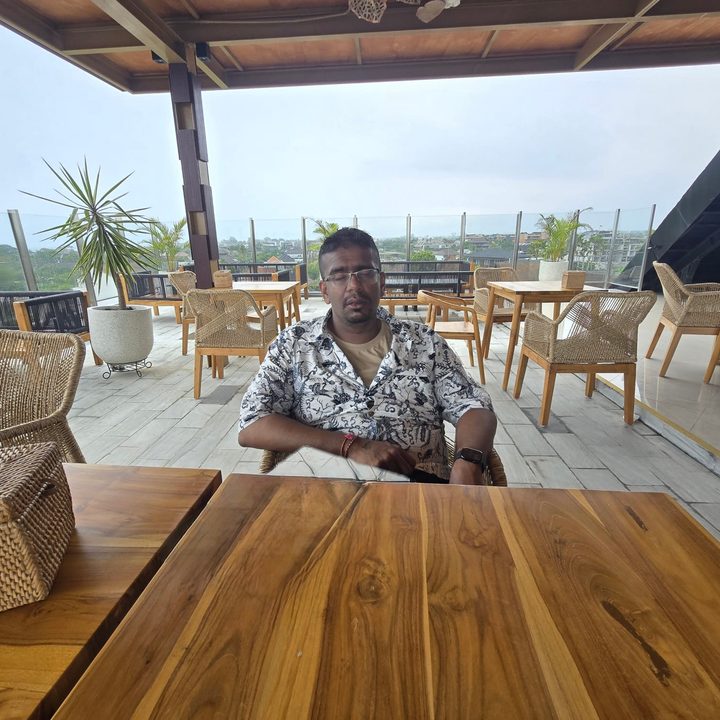 An edited photo of a person at a table with a menu in front of them with the menu removed by Apple Intelligence in the Apple Photos app