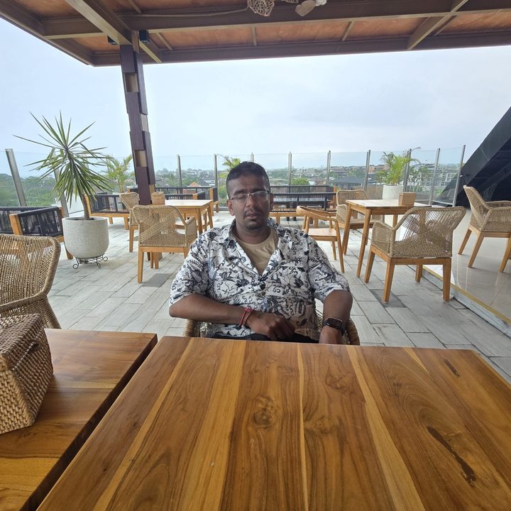 An edited photo of a person at a table with a menu in front of them with the menu removed by Google Gemini AI in the Google Photos app