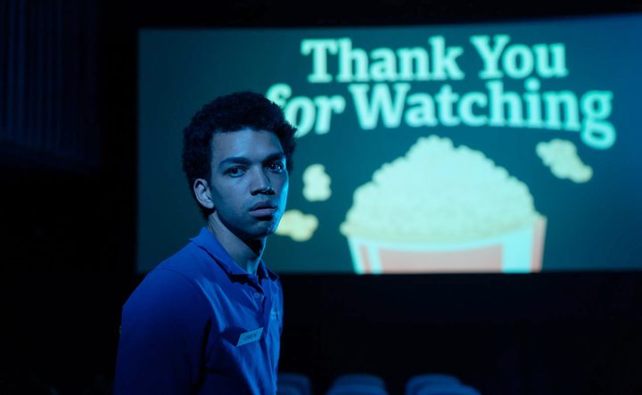 A teen man looks in a movie theater in I Saw the TV Glow.