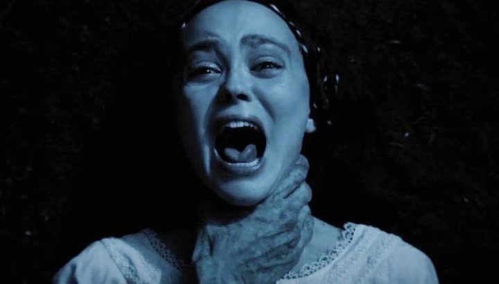 A woman screams as a hand grasps her neck in Nosferatu.