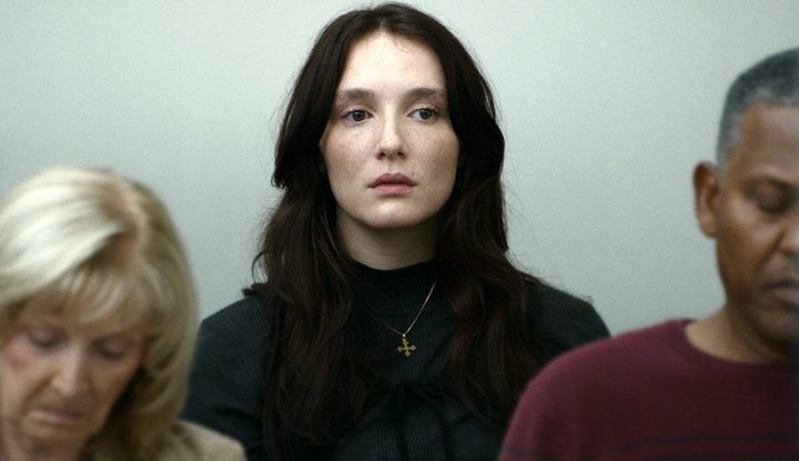 A woman sits in a courtroom in Red Rooms.