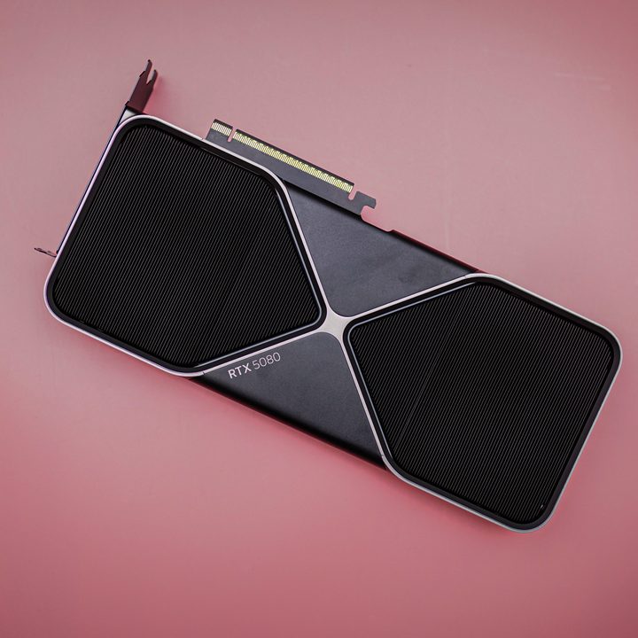The RTX 5080 sitting on a pink background.