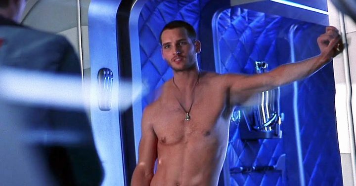 A shirtless man leans on a doorframe in Supernova.