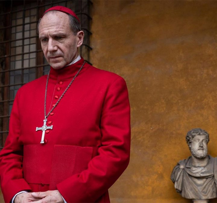 Ralph Fiennes looks very serious and red in a still from the movie Conclave.