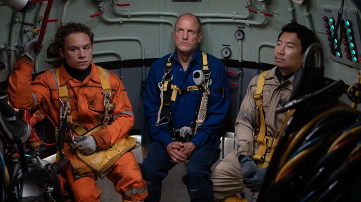 Finn Cole, Woody Harrelson, and Simu Liu sit, looking worried, in a diving bell in a still from the movie Last Breath.