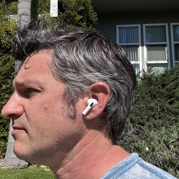 A man wearing the Apple AirPods Pro 2 outside on a sidewalk.