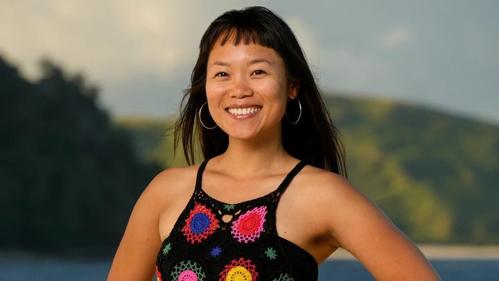 Mary from Survivor 48 posing in front of the beach at night smiling.