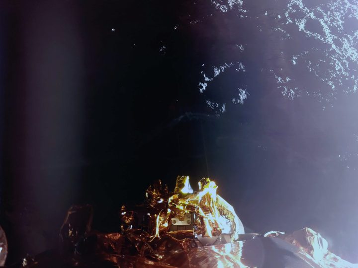 The image shows the Moon’s surface and a top-down view of the lander’s RCS thrusters (center) with a sun glare on the right side.