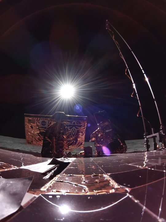 Blue Ghost caught her first look at the solar eclipse from the Moon around 12:30 am CDT on March 14 from our landing site in Mare Crisium. Notice the glowing ring of light emerge in the reflection of our solar panel as Earth began to block the sun. This photo taken from the lander's top deck also shows our X-band antenna (left), the Lunar Environment heliospheric X-ray Imager (center), and the Lunar Magnetotelluric Sounder mast (right).