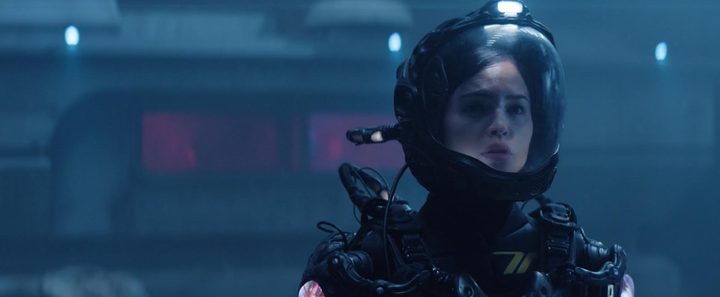 A female astronaut looks concerned in her suit.