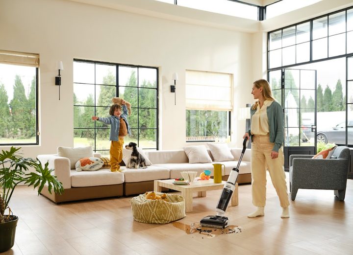 child jumps on sofa while mom vacuums