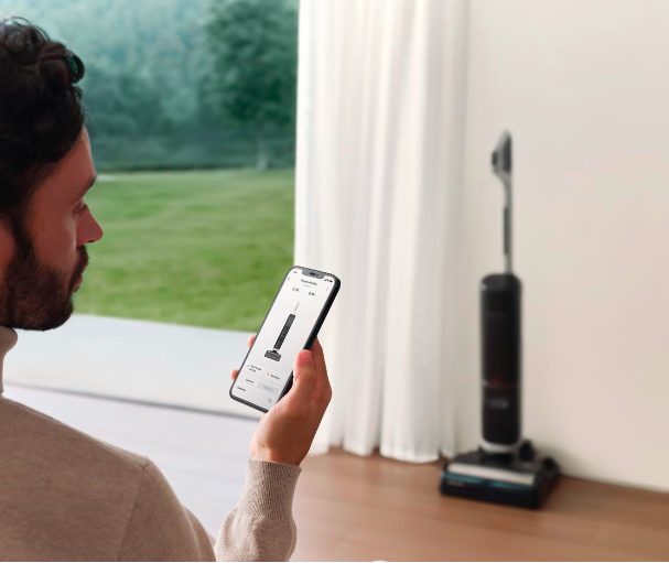 man with phone app open to manage the settings of his vacuum.