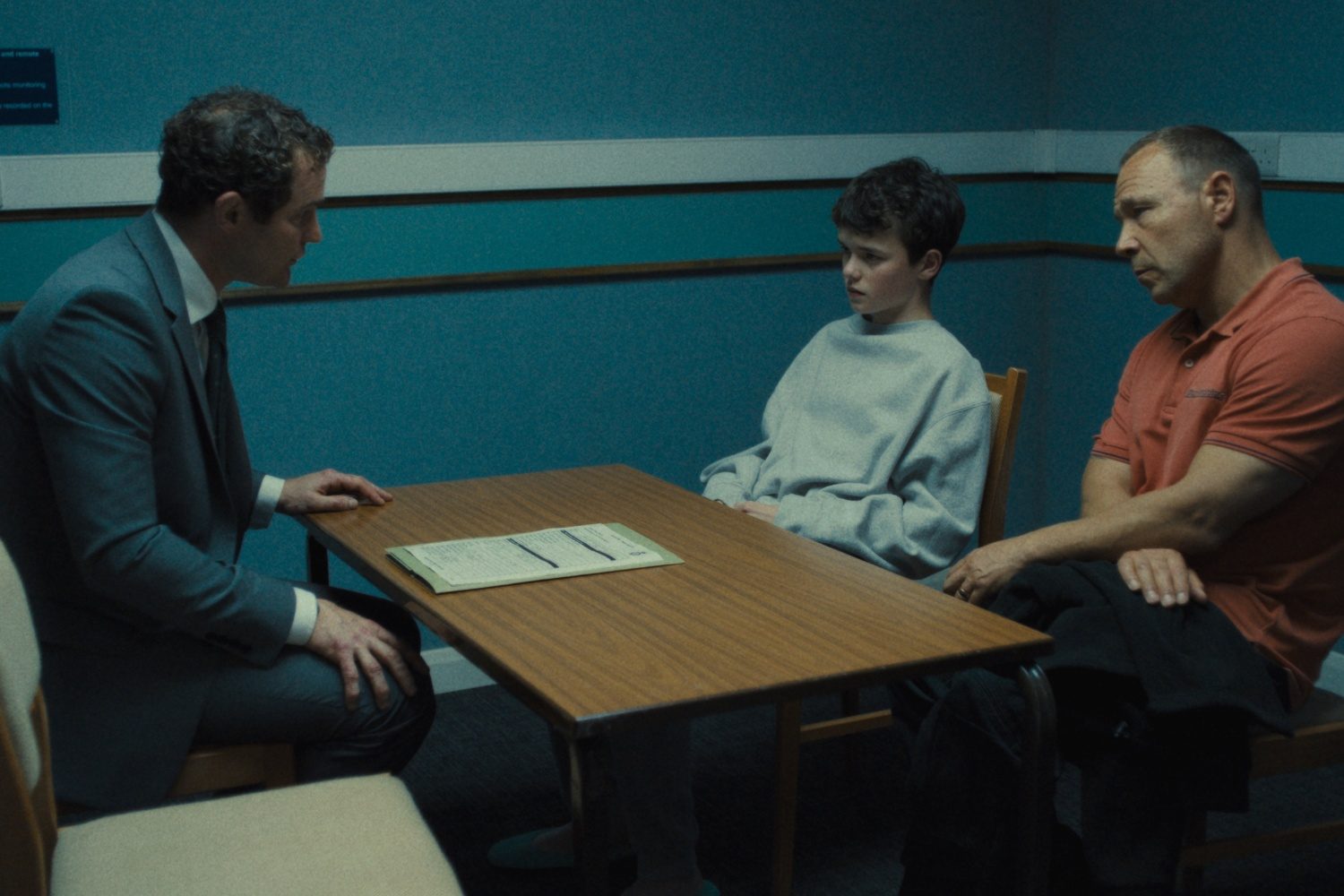 Two guys sit at the table across from a man.