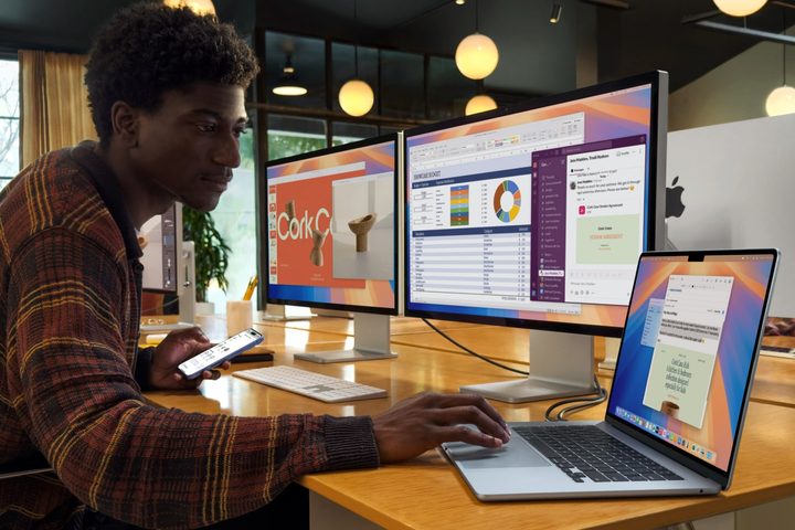 A person using the Apple MacBook Air with M4 chip and two external displays.