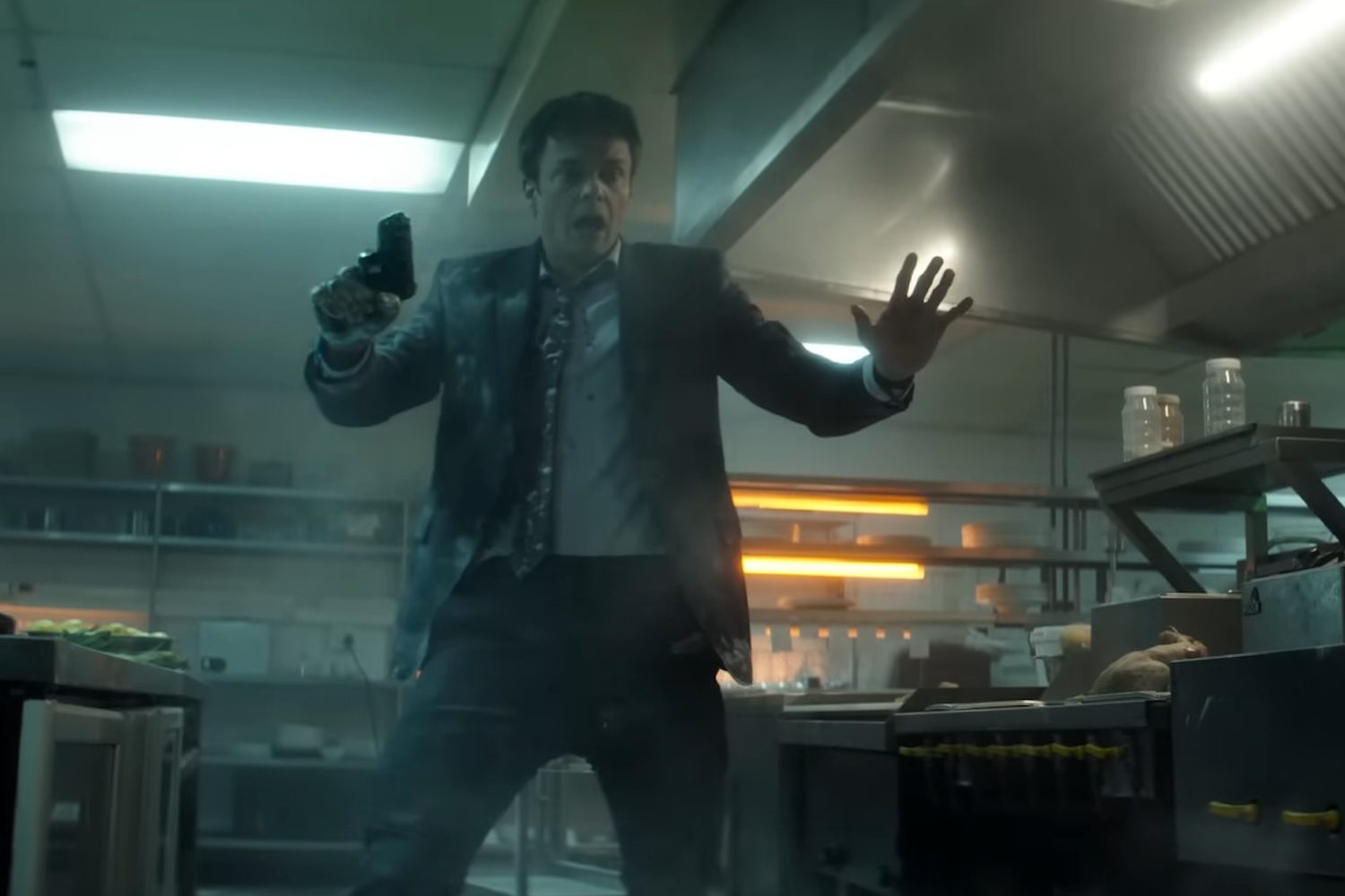 Jack Quaid holding a gun in a kitchen in 