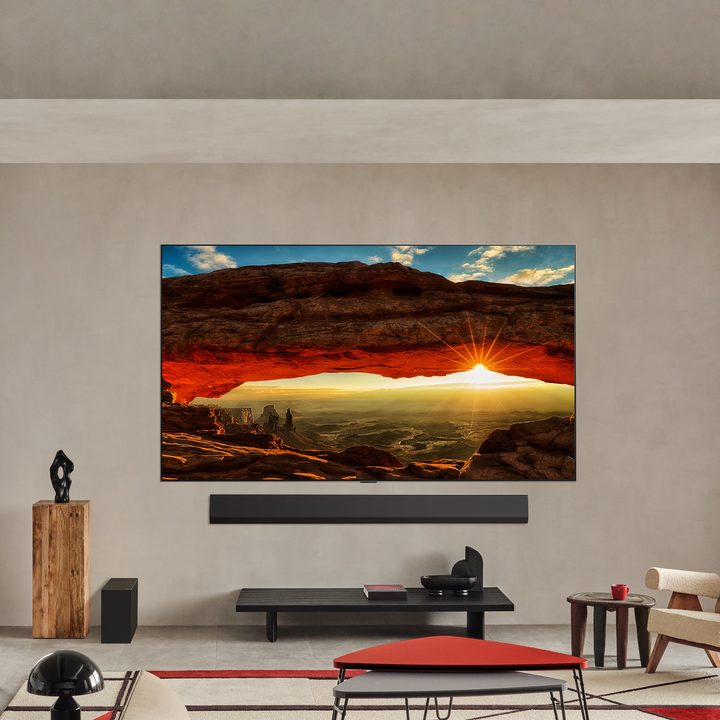 An LG G5 OLED TV hanging on a wall in a bright living room.