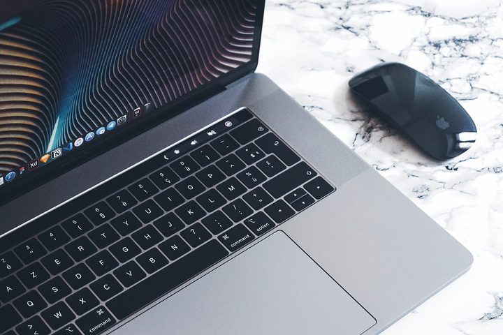 A MacBook Pro and a Magic Mouse on a desk.