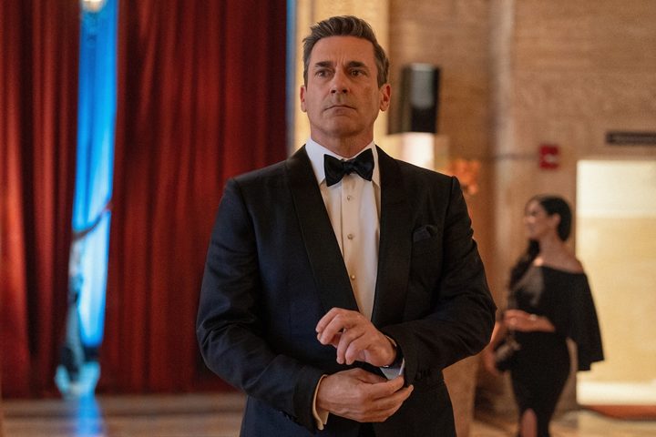 Jon Hamm fixes his cuffs while wearing a suit.