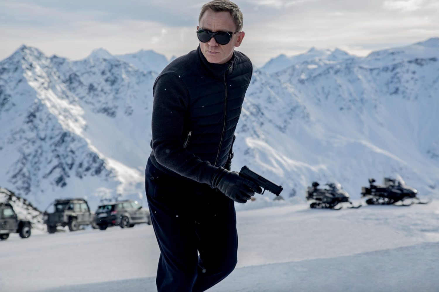 James Bond holds a gun on a mountain.