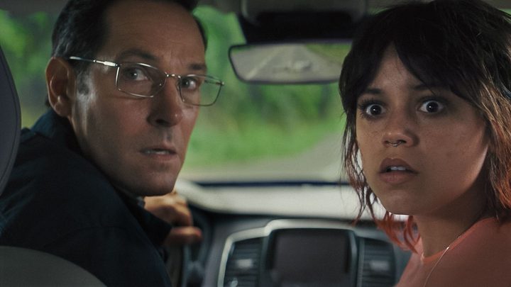 A man and woman look behind them while sitting in a car.