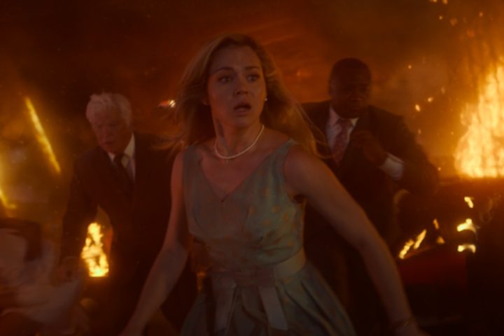 A woman cries as fire blazes behind her.
