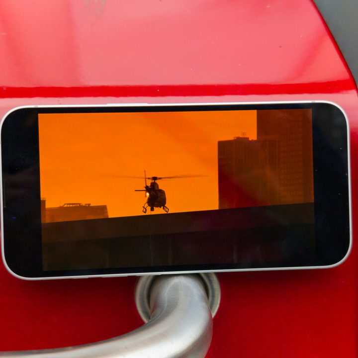The iPhone 16e screen displaying a movie with a helicopter's sillouette in the sky