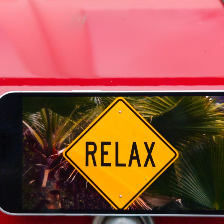 The iPhone 16e screen displaying a movie with a sign that says relax