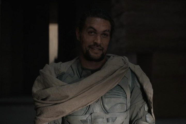 Jason Momoa stands and smirks.