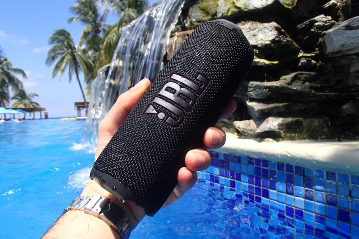 JBL Flip 7 hand-held near a pool.