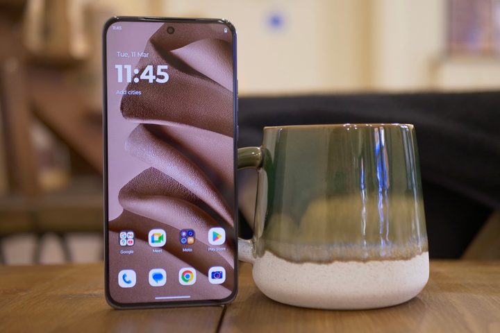 The Motorola Edge 50 Neo in Mocha Mousse next to a coffee mug.