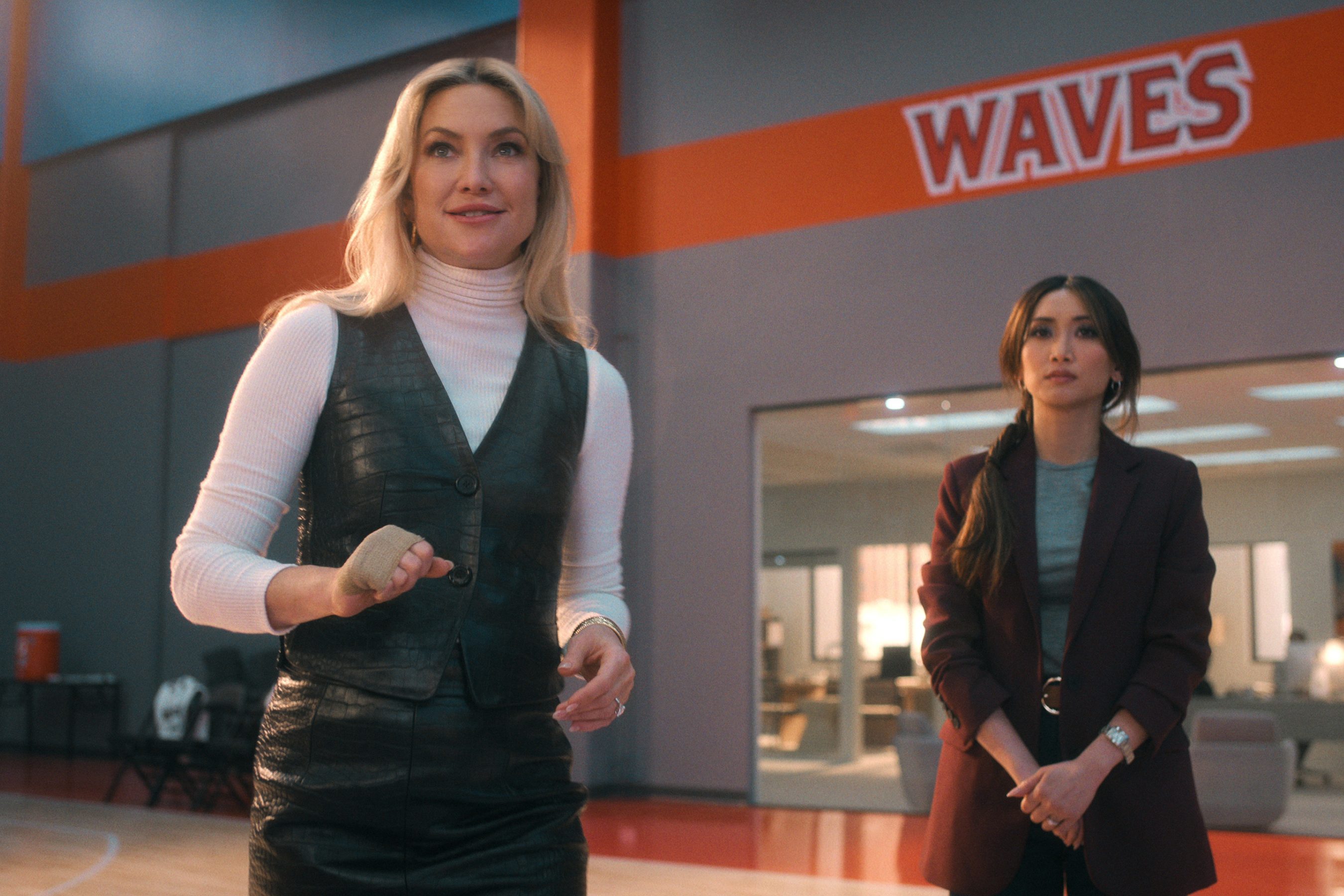 Two women stand in a gym.
