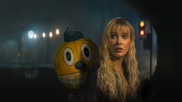 Millie Bobby Brown looks back with a robot behind her in "The Electric State."