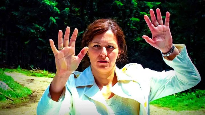 A woman outside with her hands held up like a mime in The Wall.