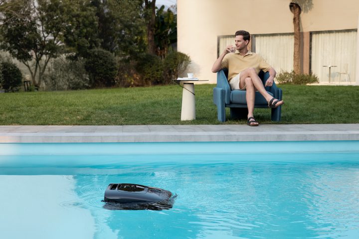 man relaxing while beatbot cleans his pool