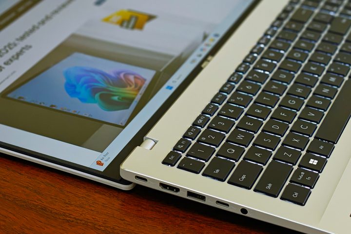 I/O ports and connectivity options on the left side of the Asus Vivobook 16 X1607QA Copilot+ PC laptop with Qualcomm Snapdragon X ARM 64 chip on a wooden surface.
