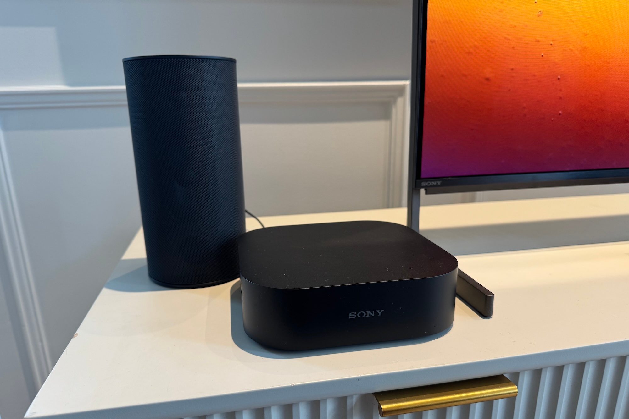 The wireless surround speaker for the Sony Bravia Theater System 6 with its wireless transmitter next to a Sony TV.