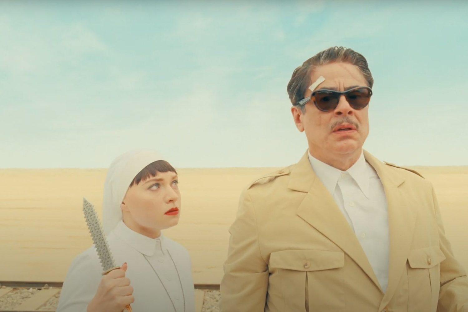 Benicio del Toro stares as a nun holds a knife up next to him.