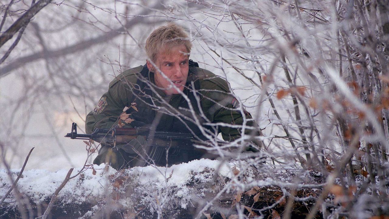 A man hides behind snowy bushes in Behind Enemy Lines.