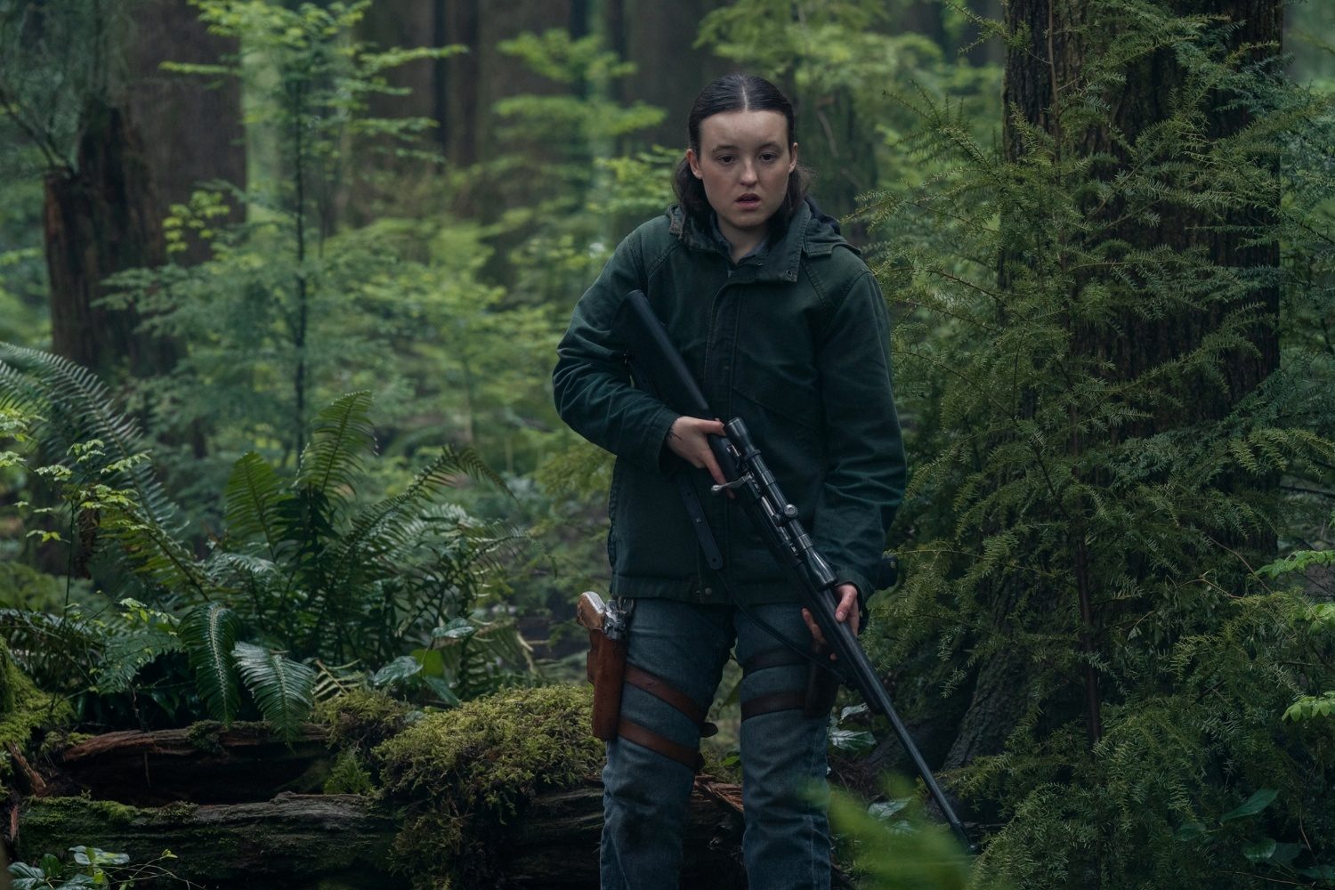 A girl walks with a gun in the forest.