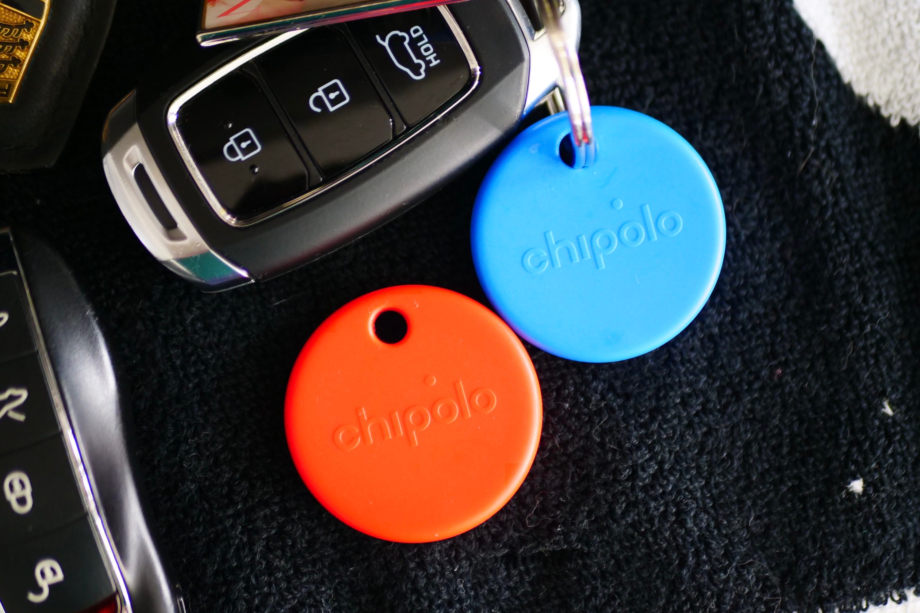 The Chipolo Pop in blue and red attached to key rings.