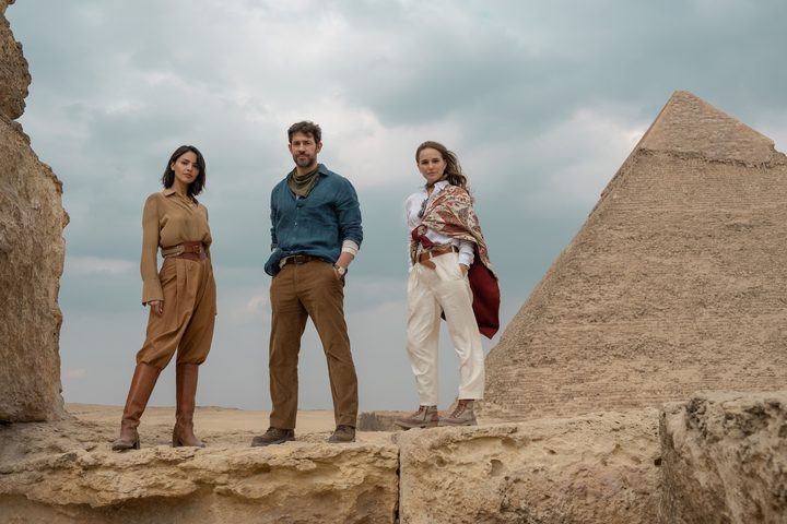 A man and two women stand in front of the pyramids.