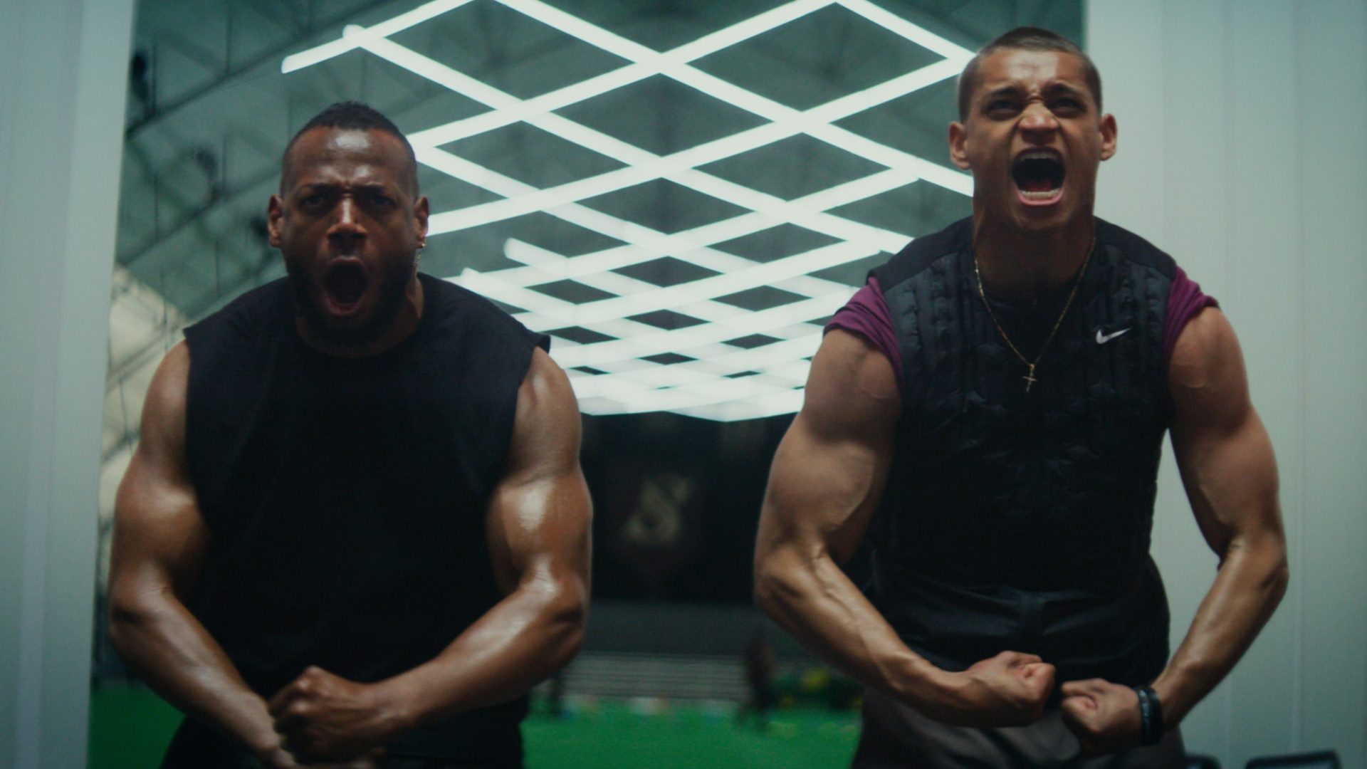 Two men flex their muscles while standing next to each other.