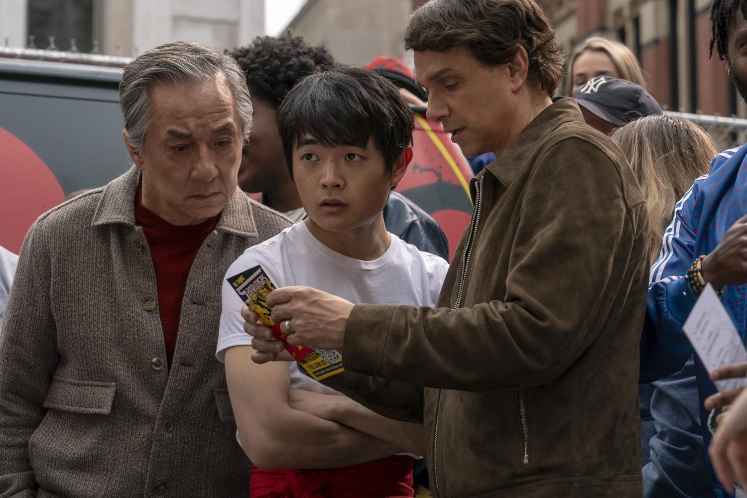 Two men look at a flyer next to a kid.