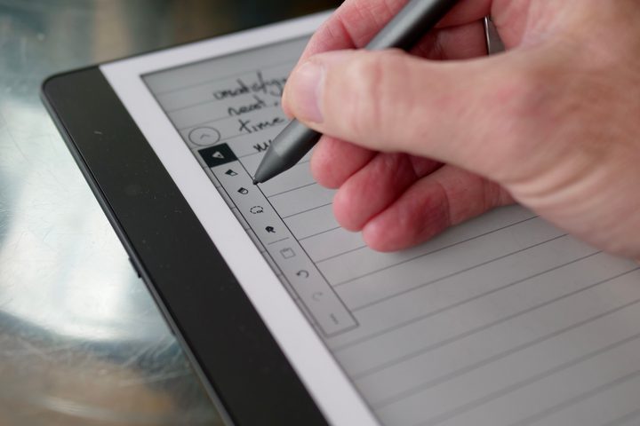 A person using the Amazon Kindle Scribe and its stylus.