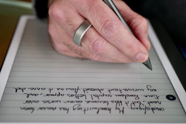 A person using the Amazon Kindle Scribe and its stylus.