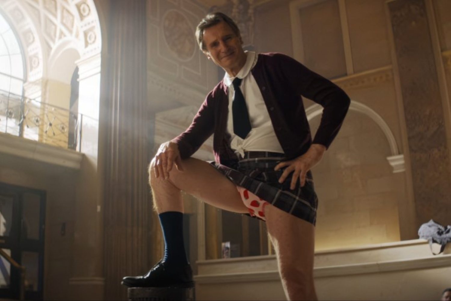 Liam Neeson stands up while weaing a skirt.